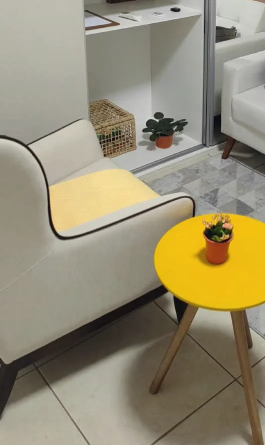 Canto da sala de espera do consultório, com poltrona clara e mesa de apoio amarela