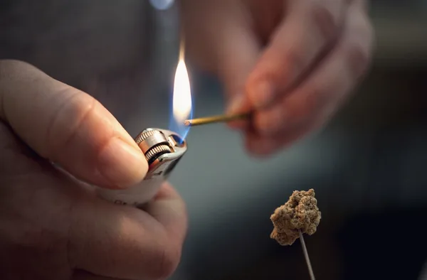 Bastão de moxa de artemísia sendo aceso antes da aplicação